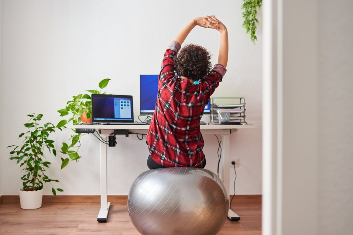 Woman Stretches While Working Out Sitting on Fitball